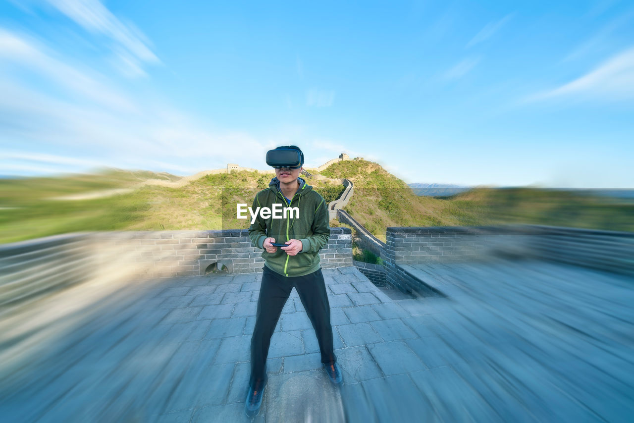 Man enjoying virtual reality simulator while standing on great wall of china