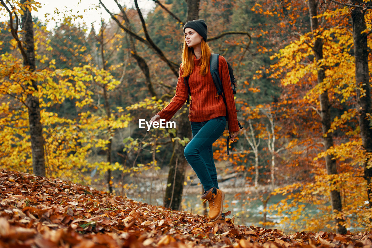 Full length of young woman in autumn leaves