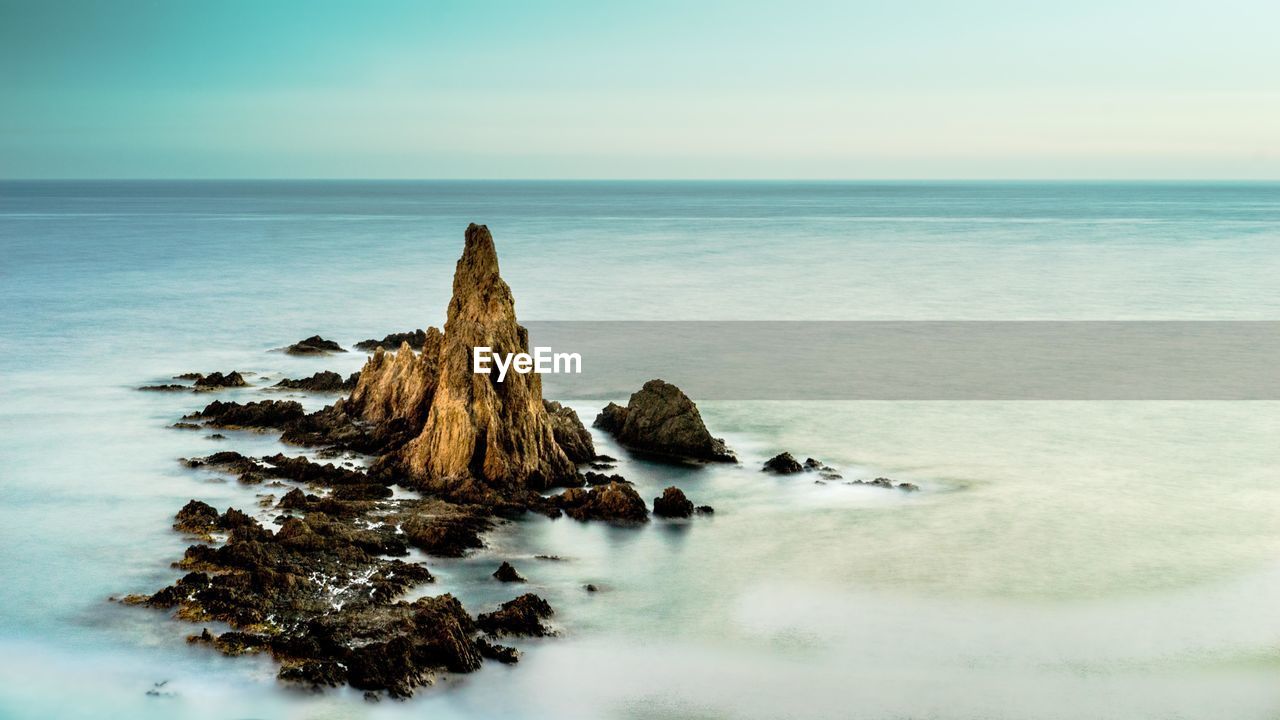 Rock formation on beach against sky