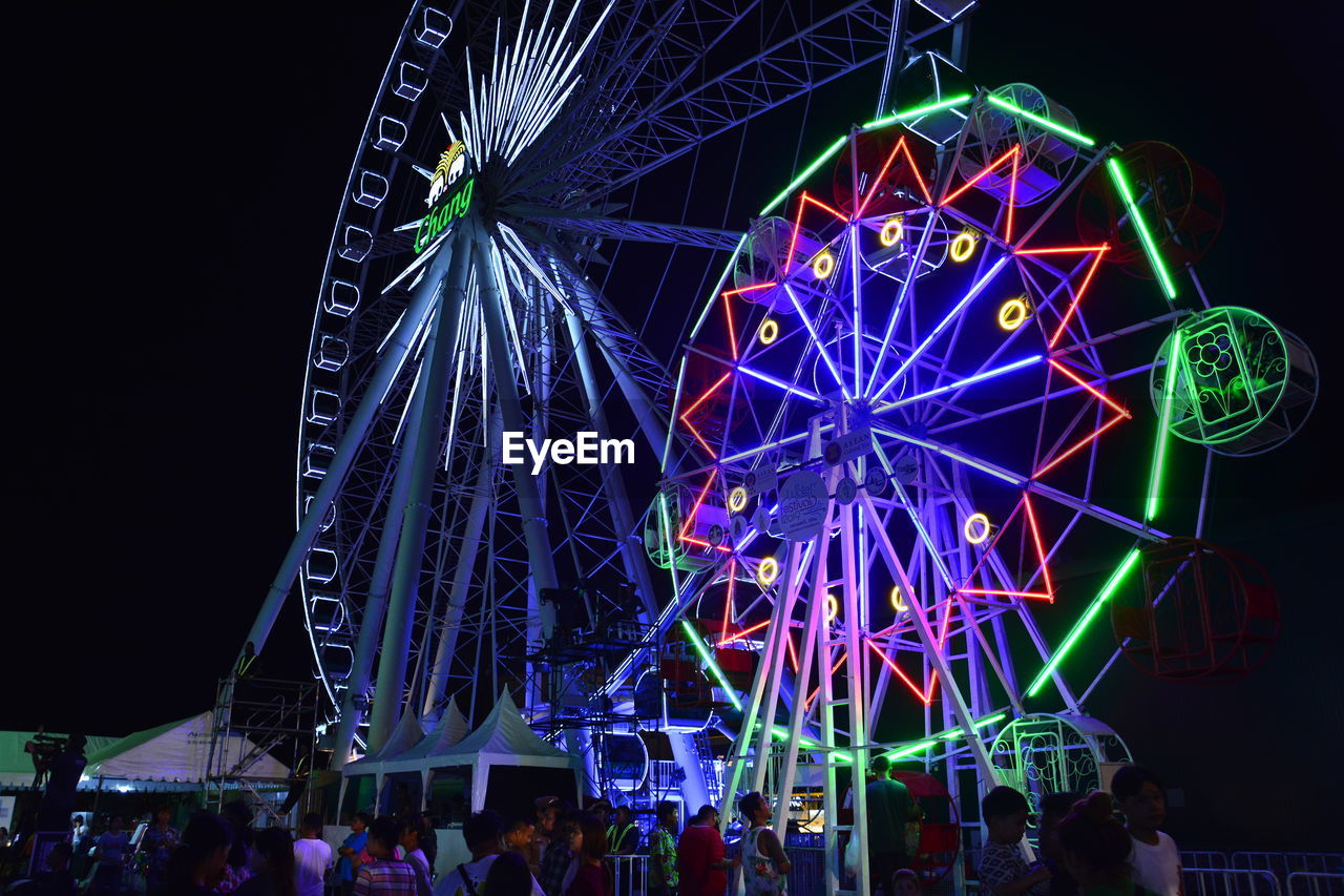 LOW ANGLE VIEW OF ILLUMINATED FERRIS WHEEL AGAINST SKY AT NIGHT