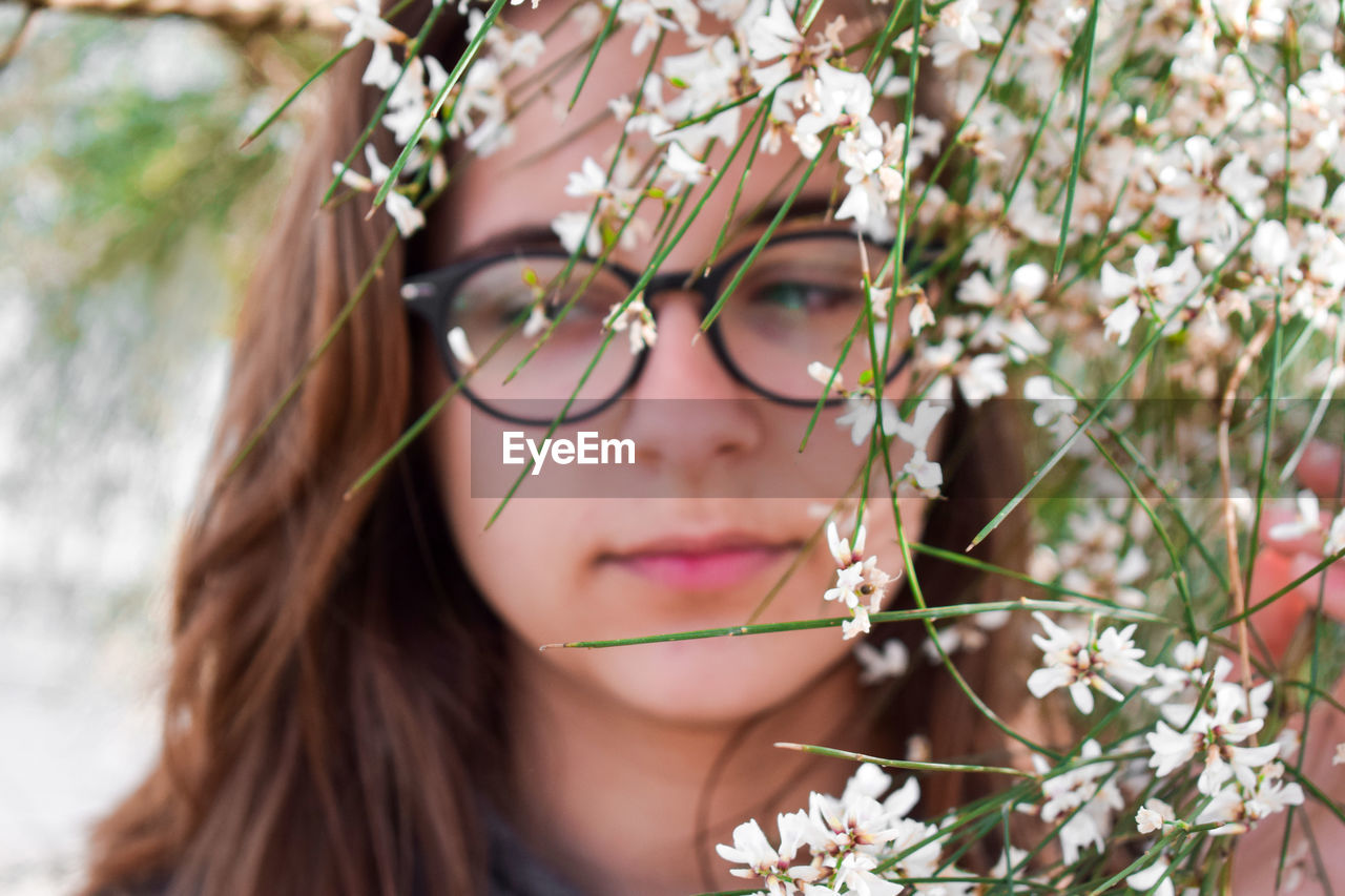 Close-up of teenage girl by white flowers