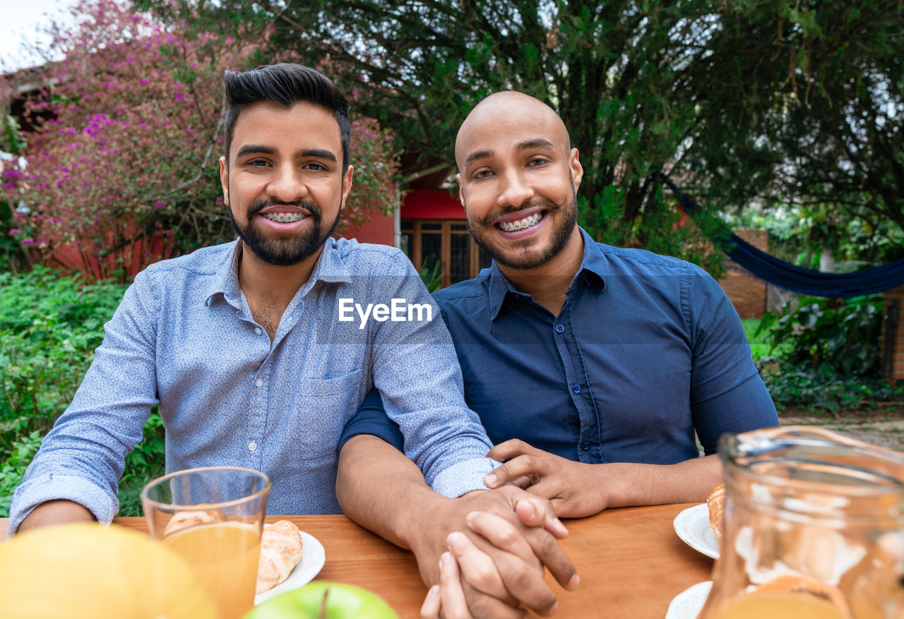 portrait of smiling friends sitting against trees