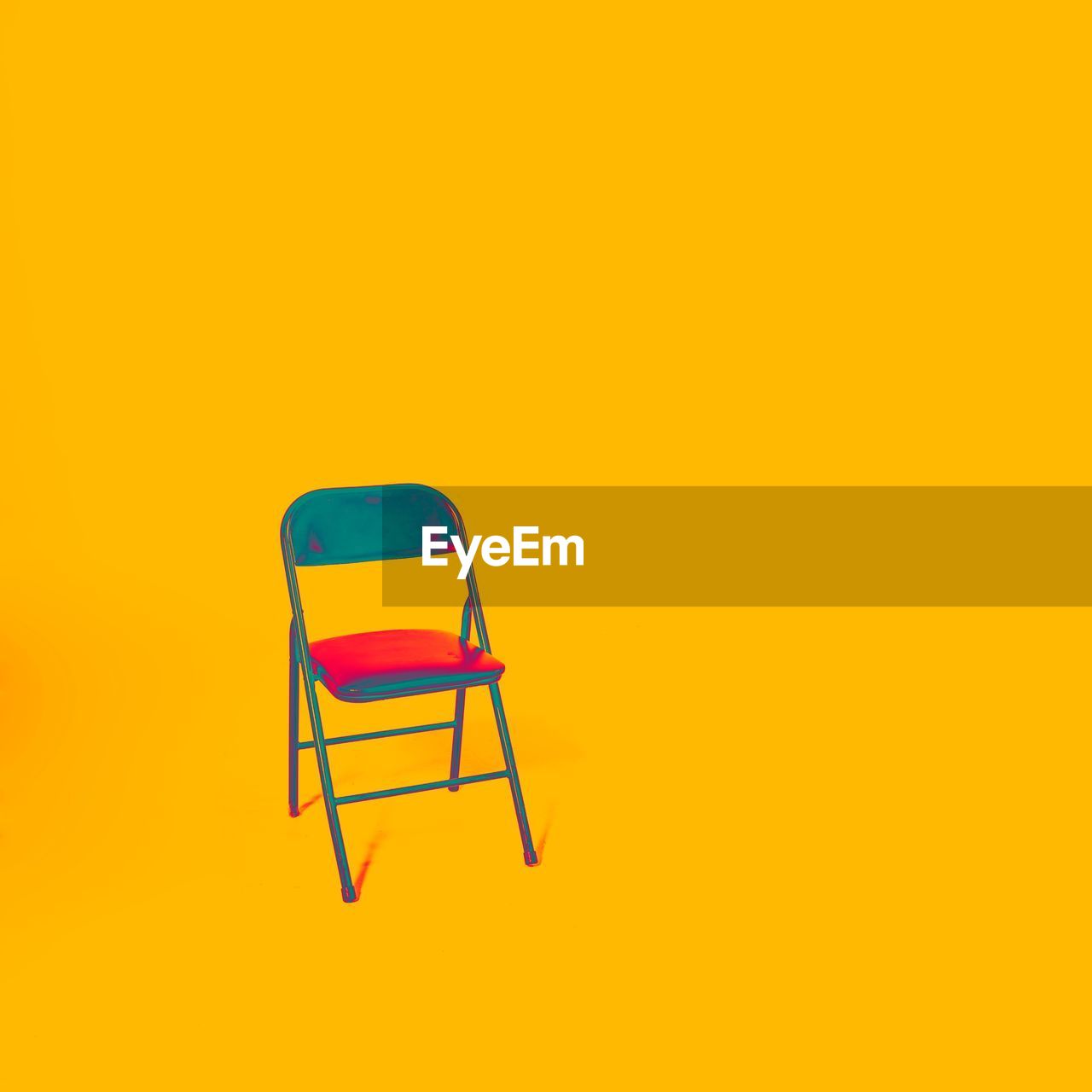 Empty chair against yellow background