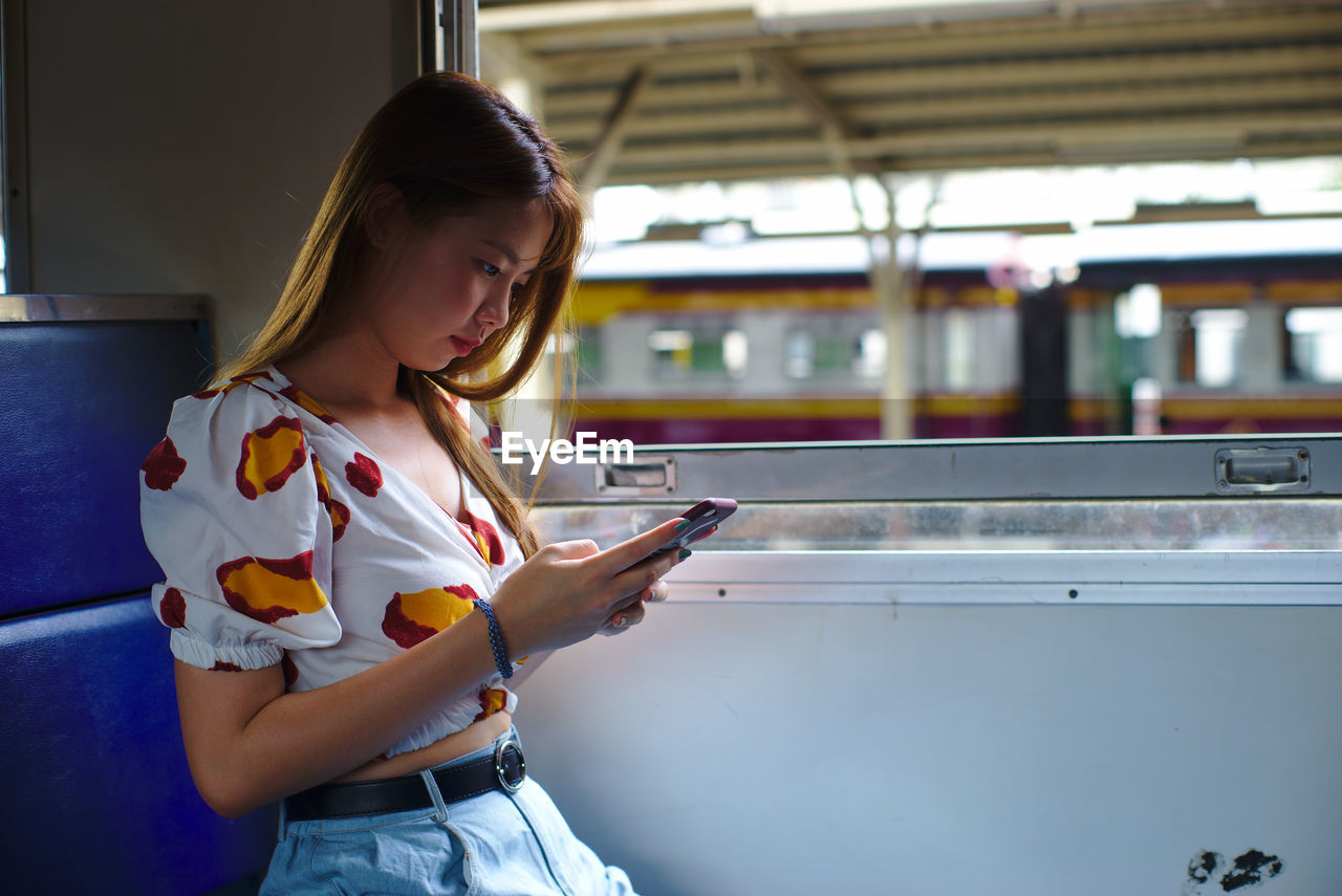 Woman using phone while traveling in train