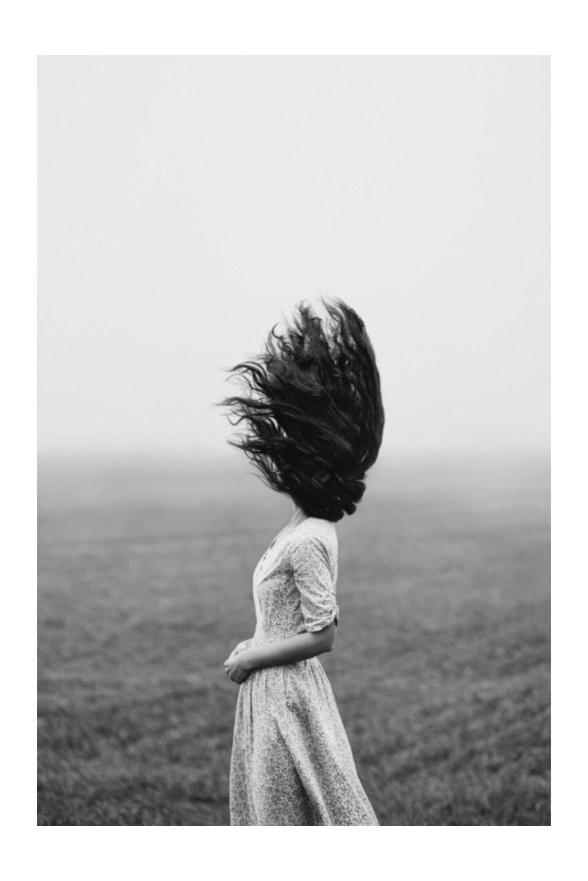 Woman with tousled hair standing on field during foggy weather