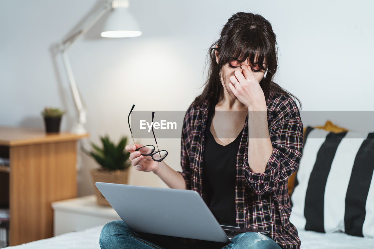 Exhausted businesswoman sitting on bed at home