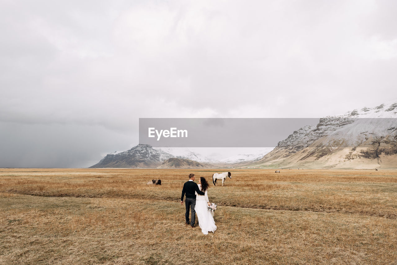 Rear view of couple walking on field