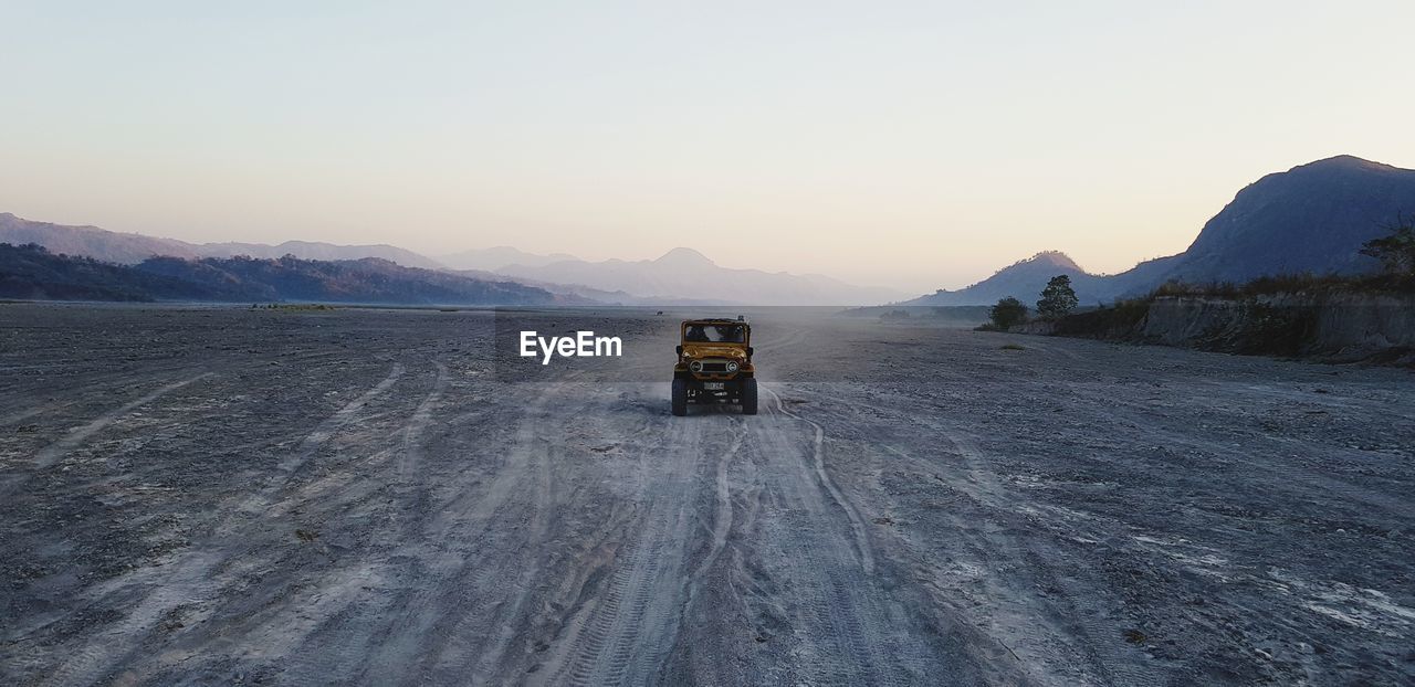 Road by snowcapped mountains against clear sky