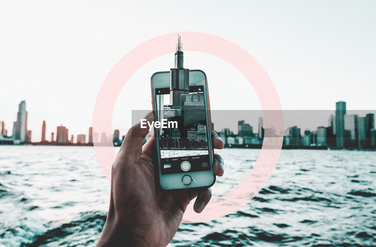 MAN PHOTOGRAPHING CITYSCAPE AGAINST CLEAR SKY