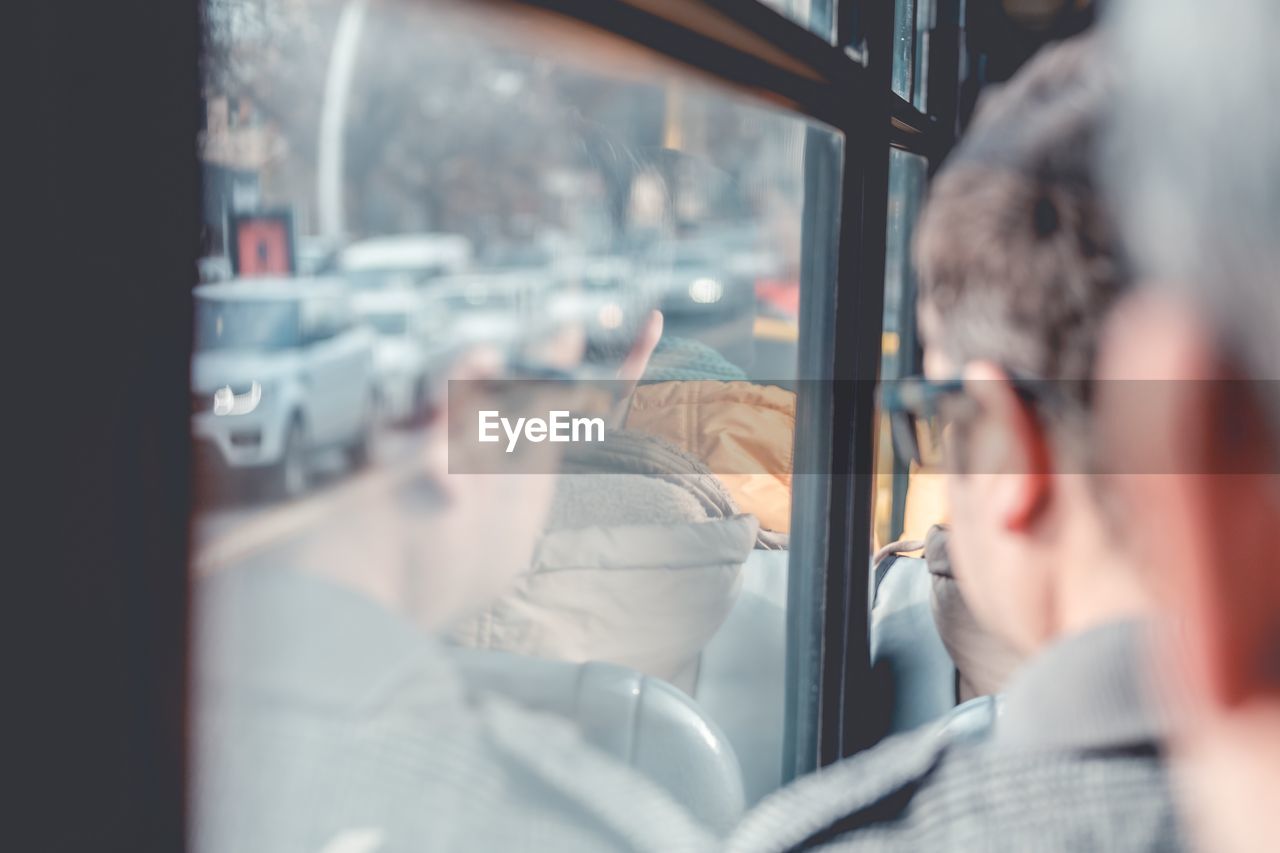 REAR VIEW OF MAN AND WOMAN LOOKING THROUGH WINDOW