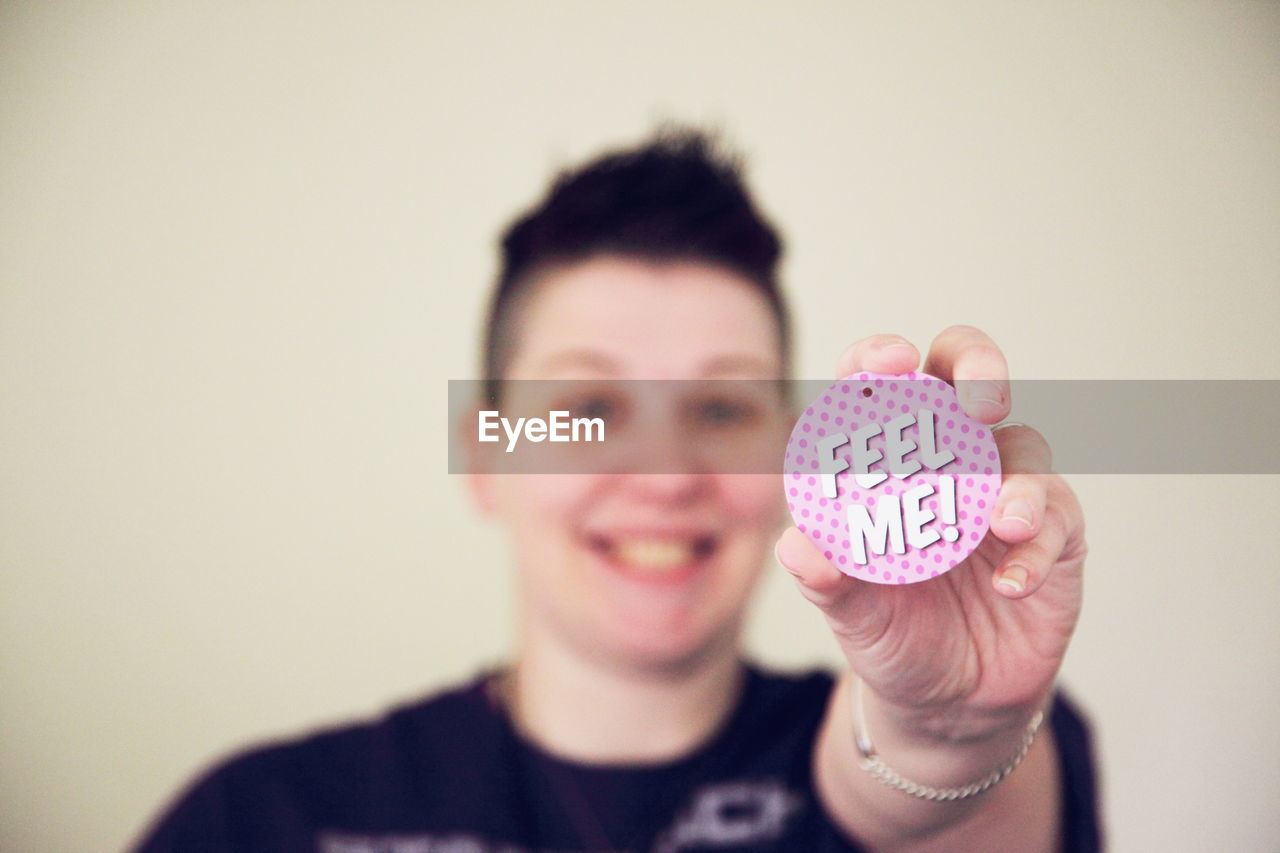 Smiling woman holding badge with text