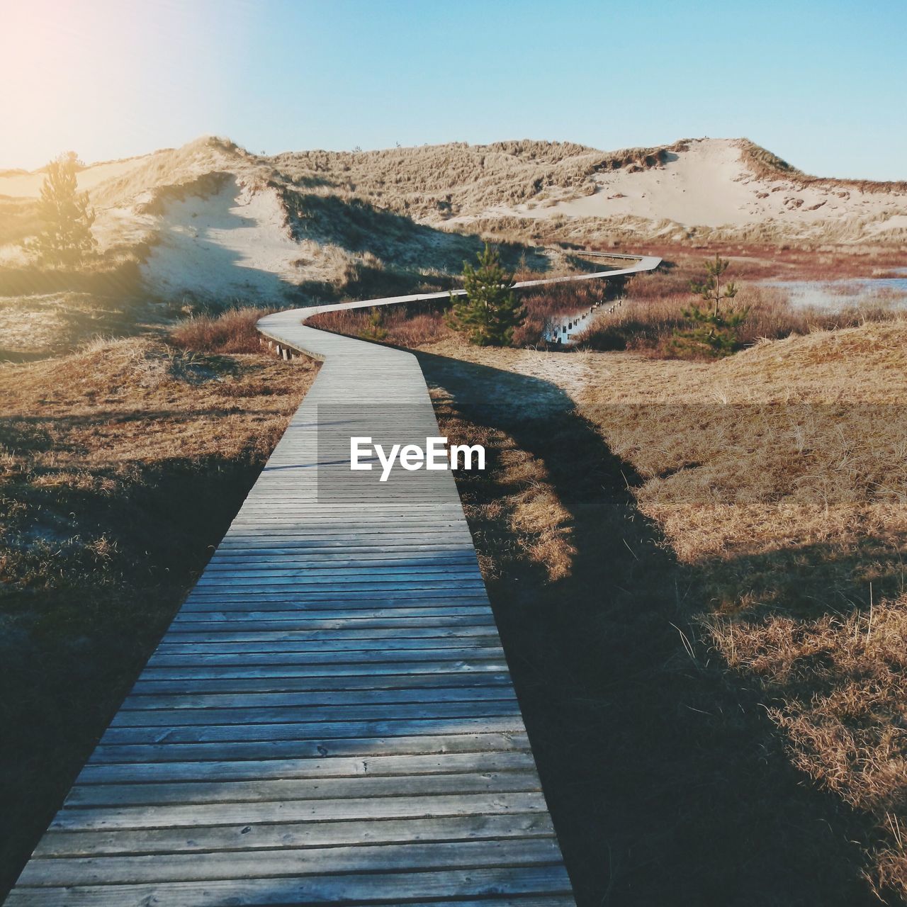 Boardwalk leading towards mountains against clear sky