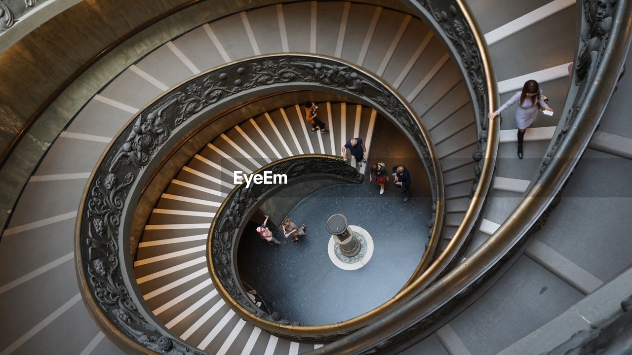 HIGH ANGLE VIEW OF PEOPLE WALKING ON SPIRAL STAIRCASE