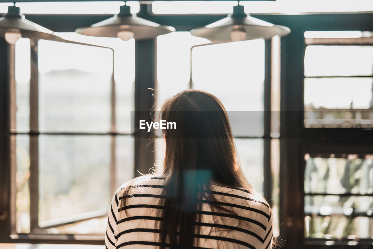 Rear view of woman looking through window
