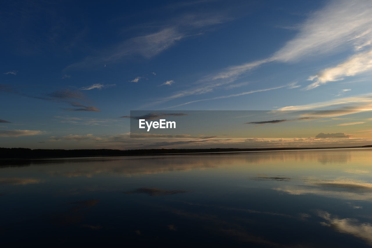 Nightfall moonlit blue sky reflected in calm lake water