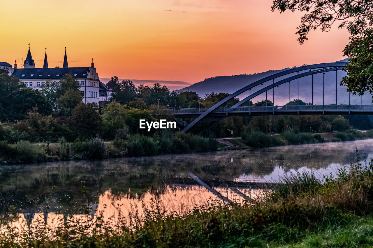 VIEW OF BRIDGE OVER RIVER AGAINST ORANGE SKY