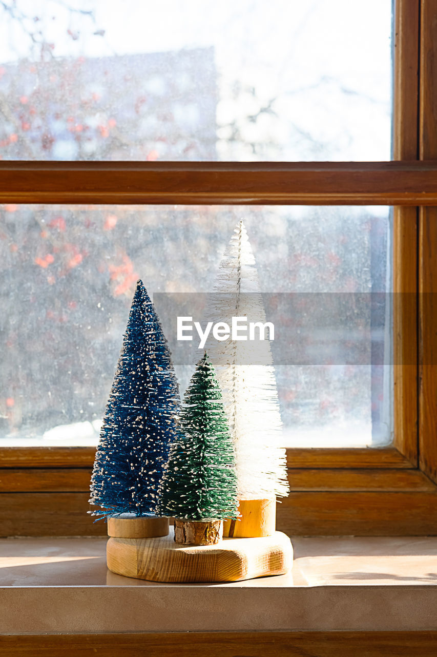Colourful christmas trees on the window. trendy home decor for winter holidays.
