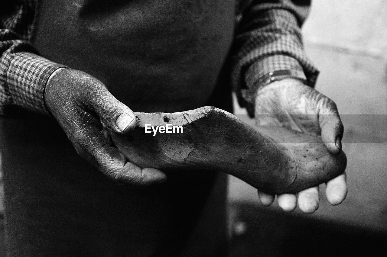 Midsection of shoemaker holding shoe in workshop