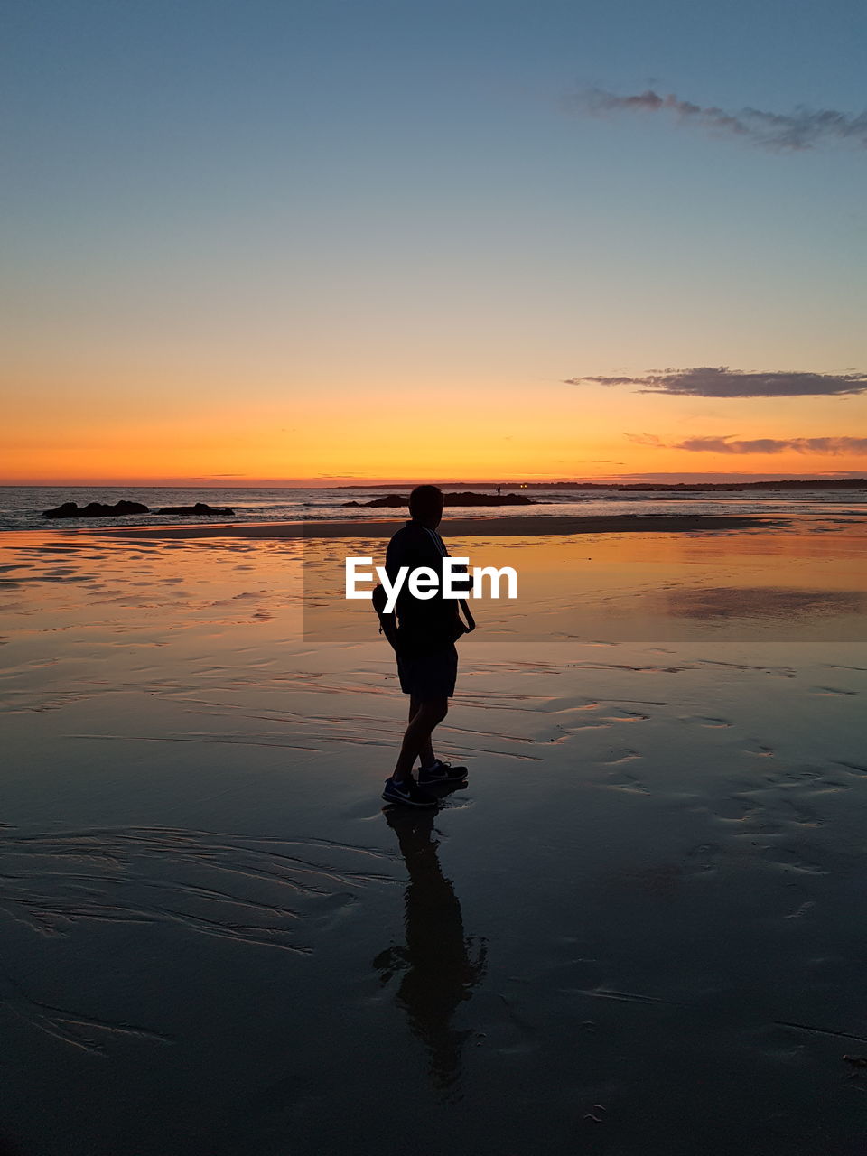 Silhouette man standing on beach against sky during sunset