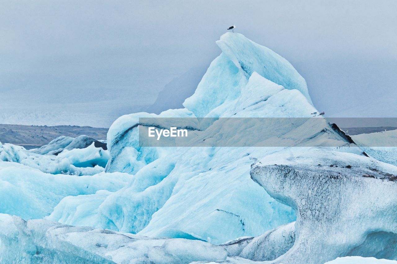 Glacier in sea against sky