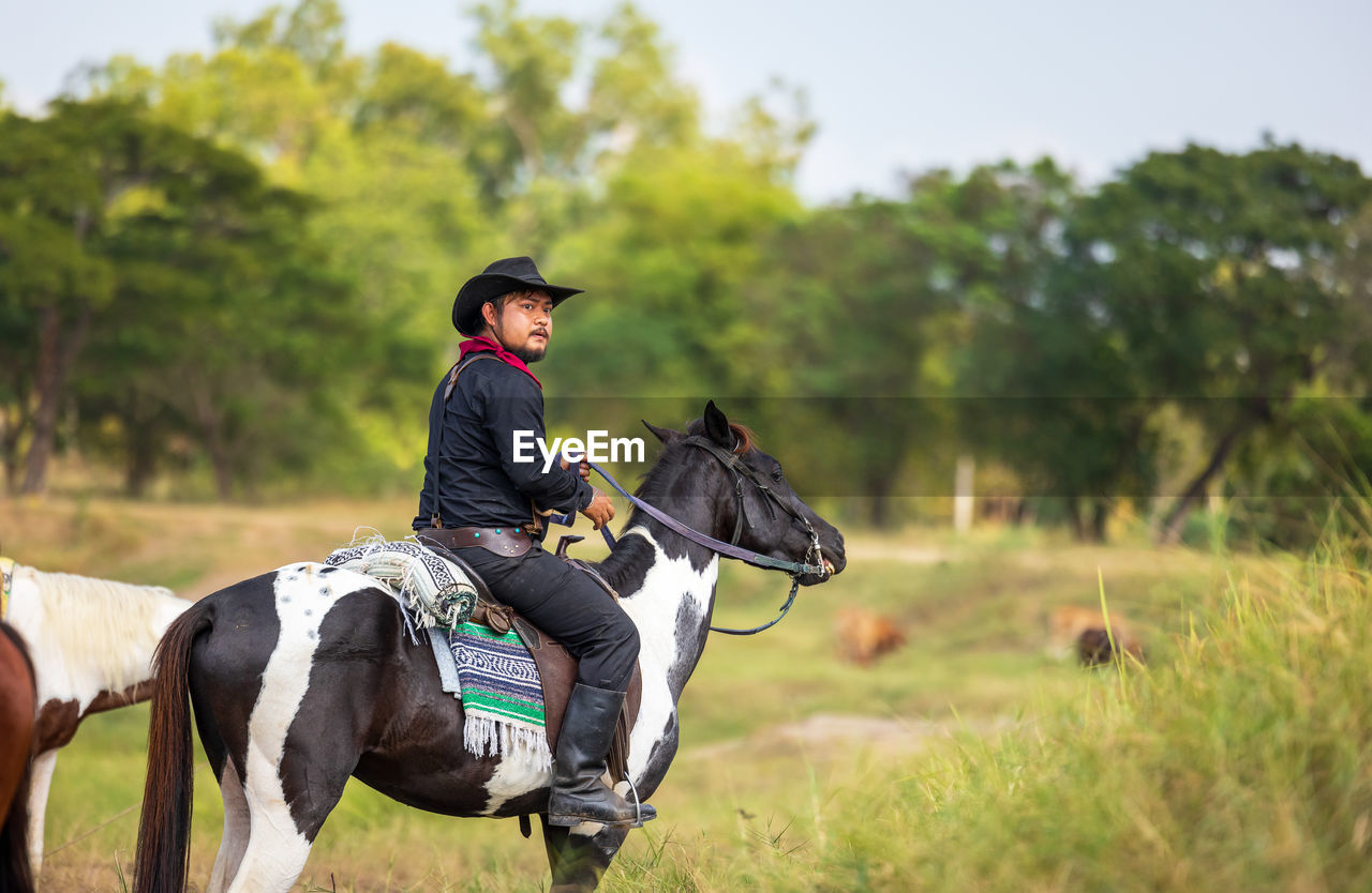 Cowboy's way of life include riding a horse around locales.