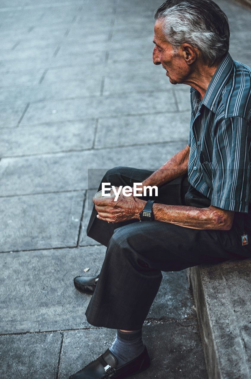 MAN USING MOBILE PHONE WHILE SITTING ON CAMERA