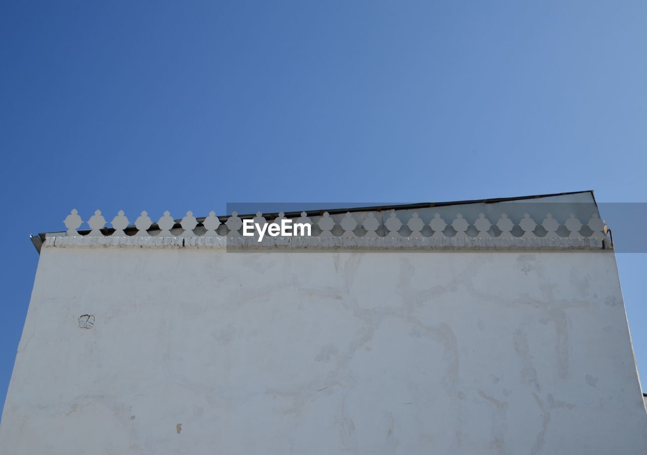 LOW ANGLE VIEW OF BUILDING WALL AGAINST BLUE SKY