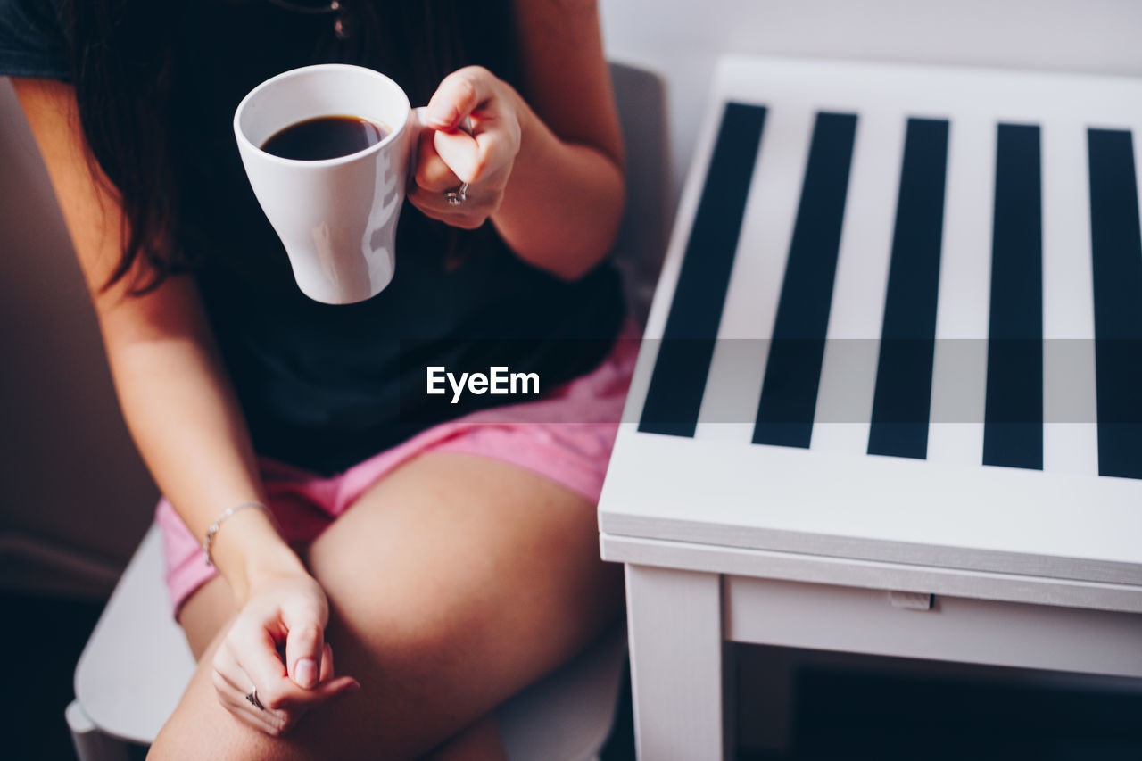 Midsection of woman holding coffee cup