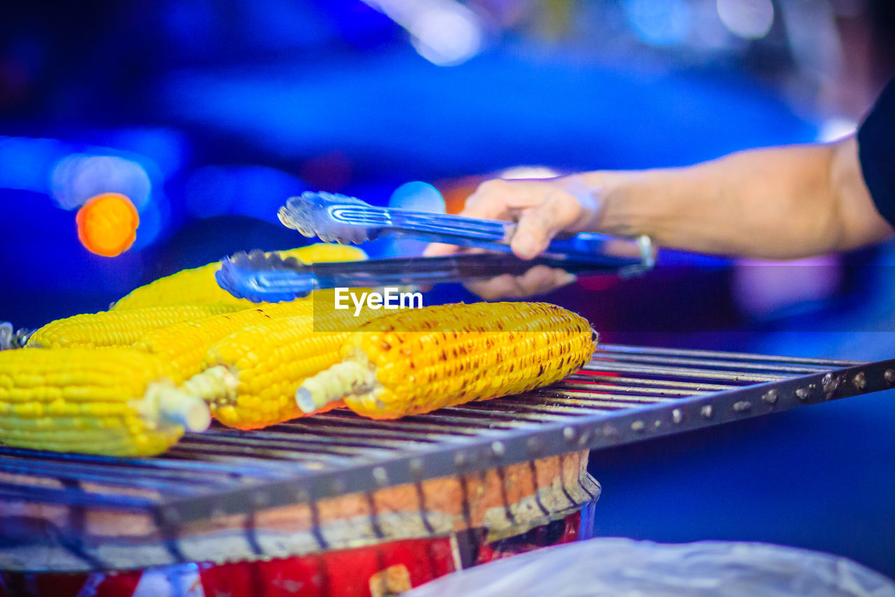 CLOSE-UP OF MAN PREPARING FOOD ON BARBECUE GRILL