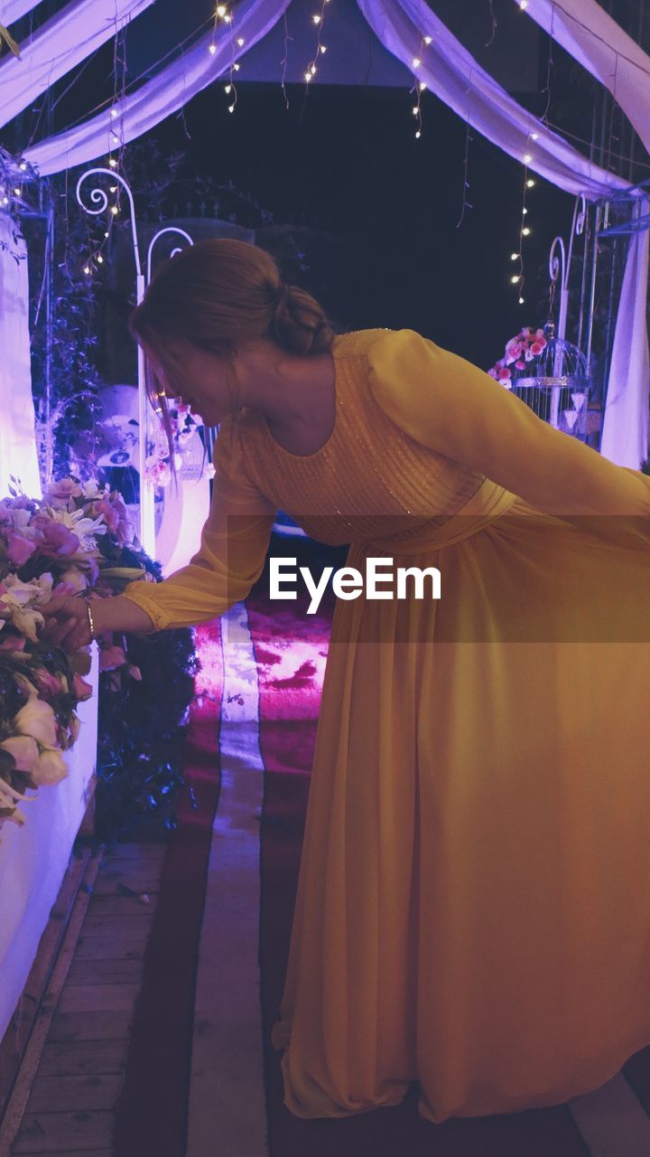 Woman touching flowers at celebration event during night