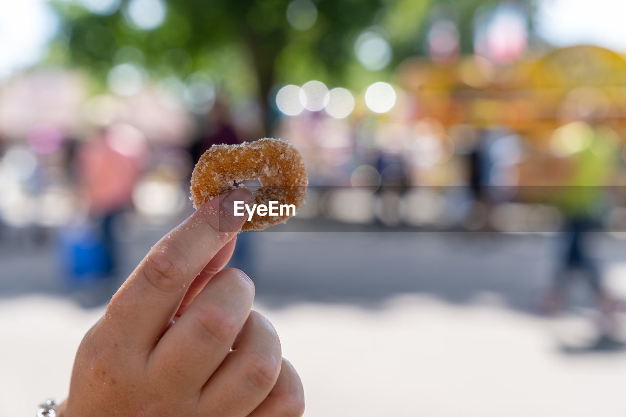 CLOSE-UP OF HAND HOLDING ICE CREAM CONE OUTDOORS