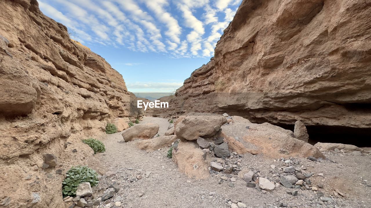 rock, wadi, rock formation, nature, sky, scenics - nature, landscape, environment, beauty in nature, land, valley, cloud, non-urban scene, desert, geology, travel destinations, no people, climate, travel, tranquility, mountain, arid climate, physical geography, extreme terrain, day, arch, canyon, outdoors, eroded, tranquil scene, sunlight, formation, plant, terrain, dry, mountain range, remote, semi-arid