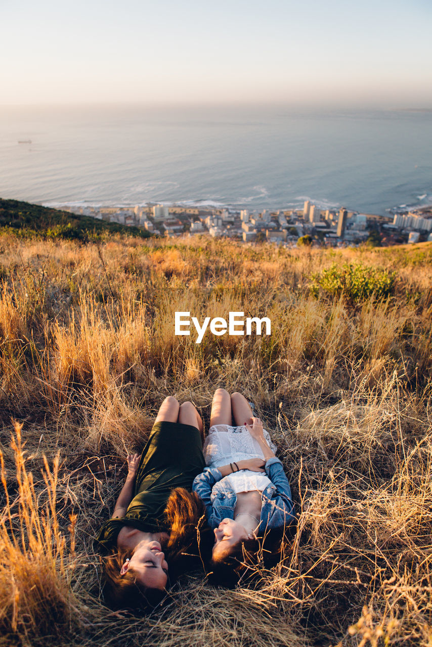 PEOPLE LYING ON FIELD BY SEA