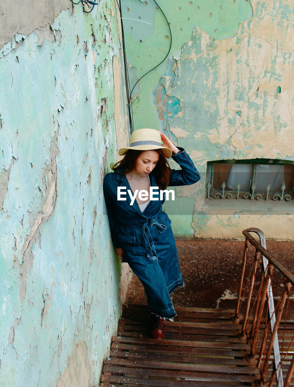 Portrait of young woman standing against wall