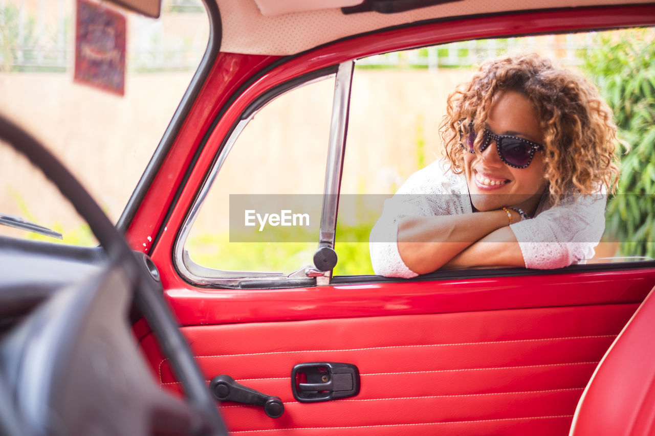 Woman smiling while leaning on car door