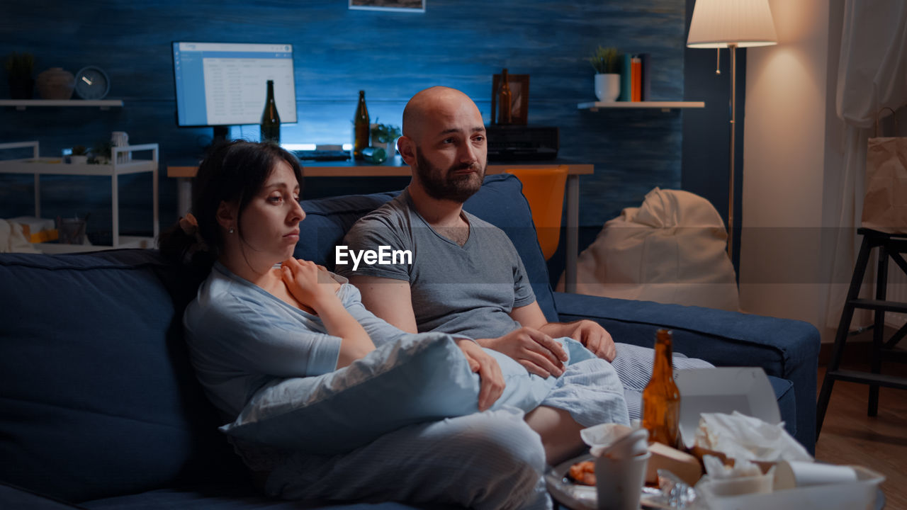 Couple watching movie while sitting on sofa at home