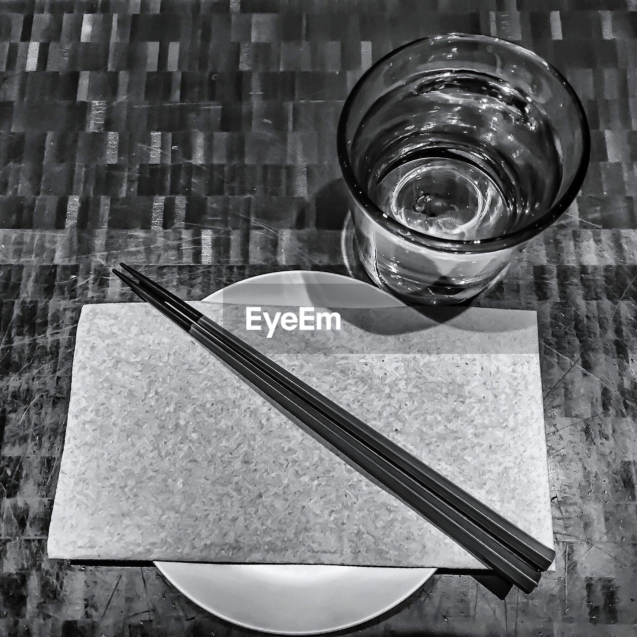 High angle view of chopsticks with menu and drinking glass on table