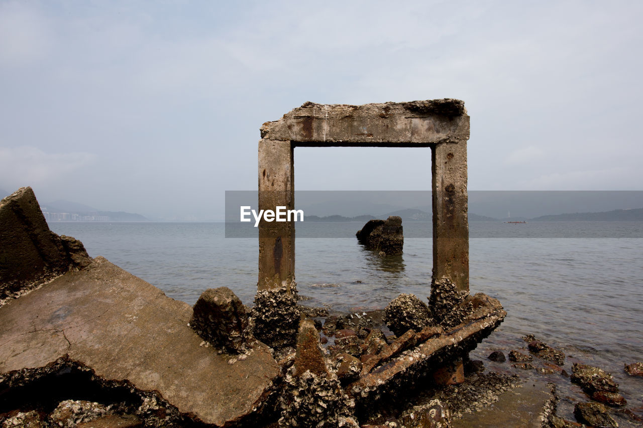 Scenic view of man made formations on sea against cloudy sky