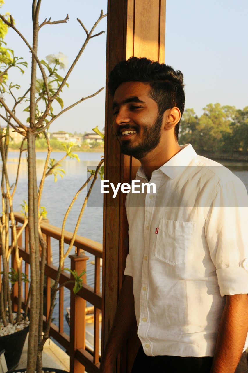 Smiling young man standing by railing