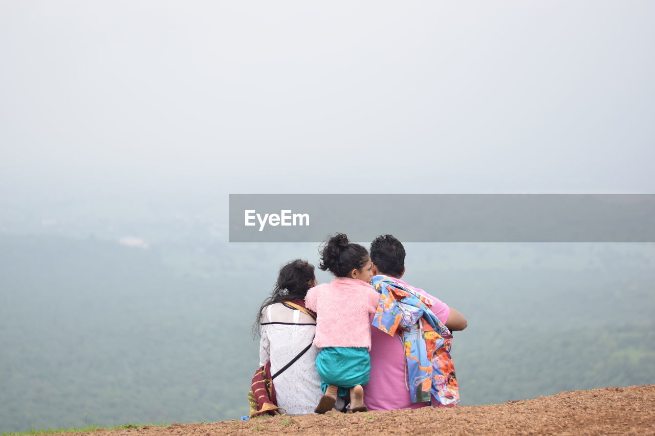 REAR VIEW OF PEOPLE LOOKING AT VIEW OF MOUNTAIN