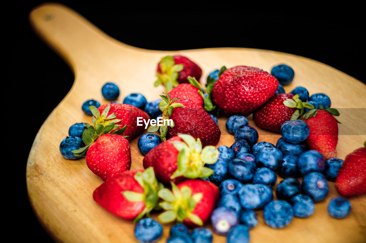 Closed up of strawberries and blueberry on wooden table with black background 