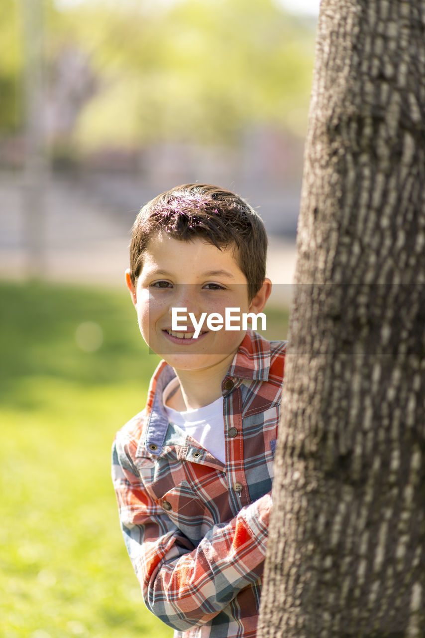 Portrait of smiling boy standing by tree