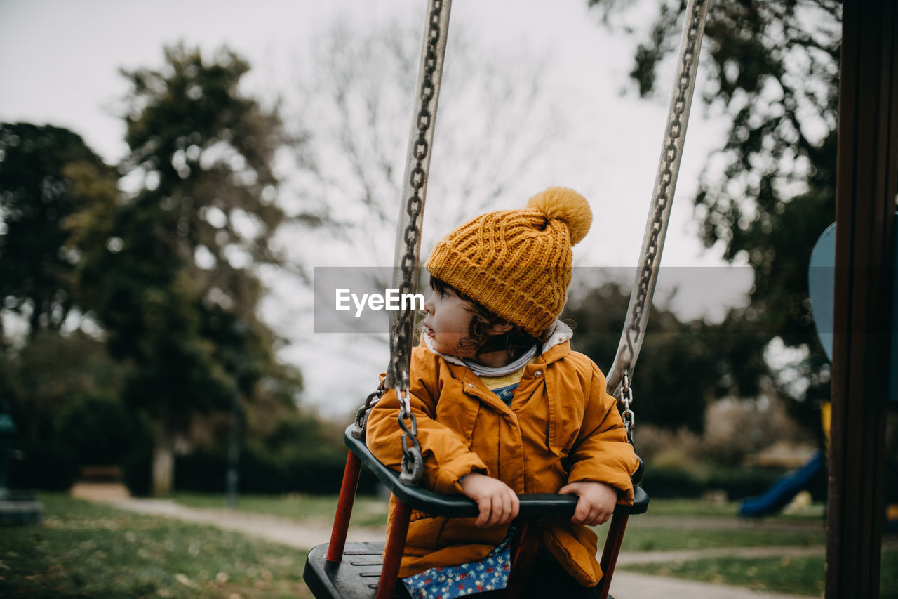 Girl sitting on swing in playground