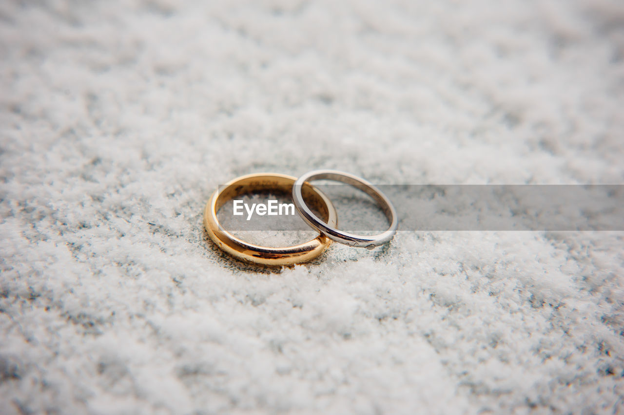 CLOSE-UP OF WEDDING RINGS ON STONE