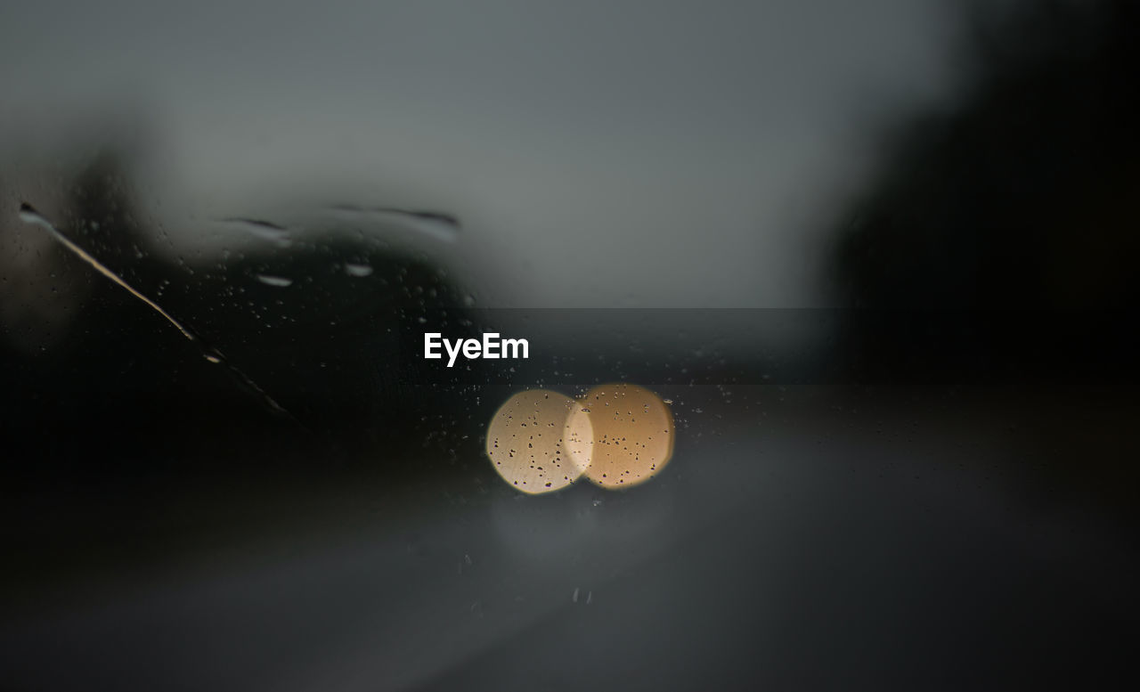 Close-up of bokeh lights and raindrops on glass