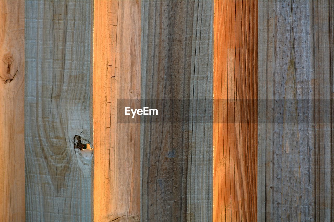 Close-up of wooden fencing backlit by setting sun