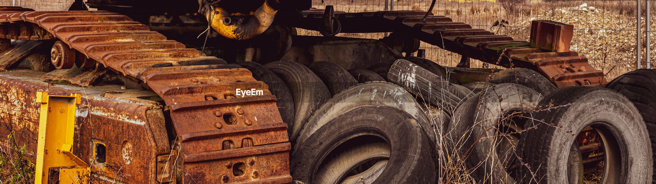 Rusty and dirt covered mechanical caterpillar track with aged cogs and wheels.