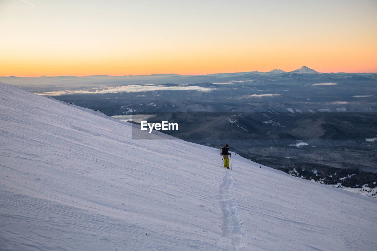 Man skiing on snowcapped mountain during sunset