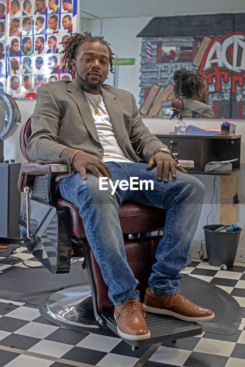 FULL LENGTH PORTRAIT OF MAN SITTING ON CHAIR