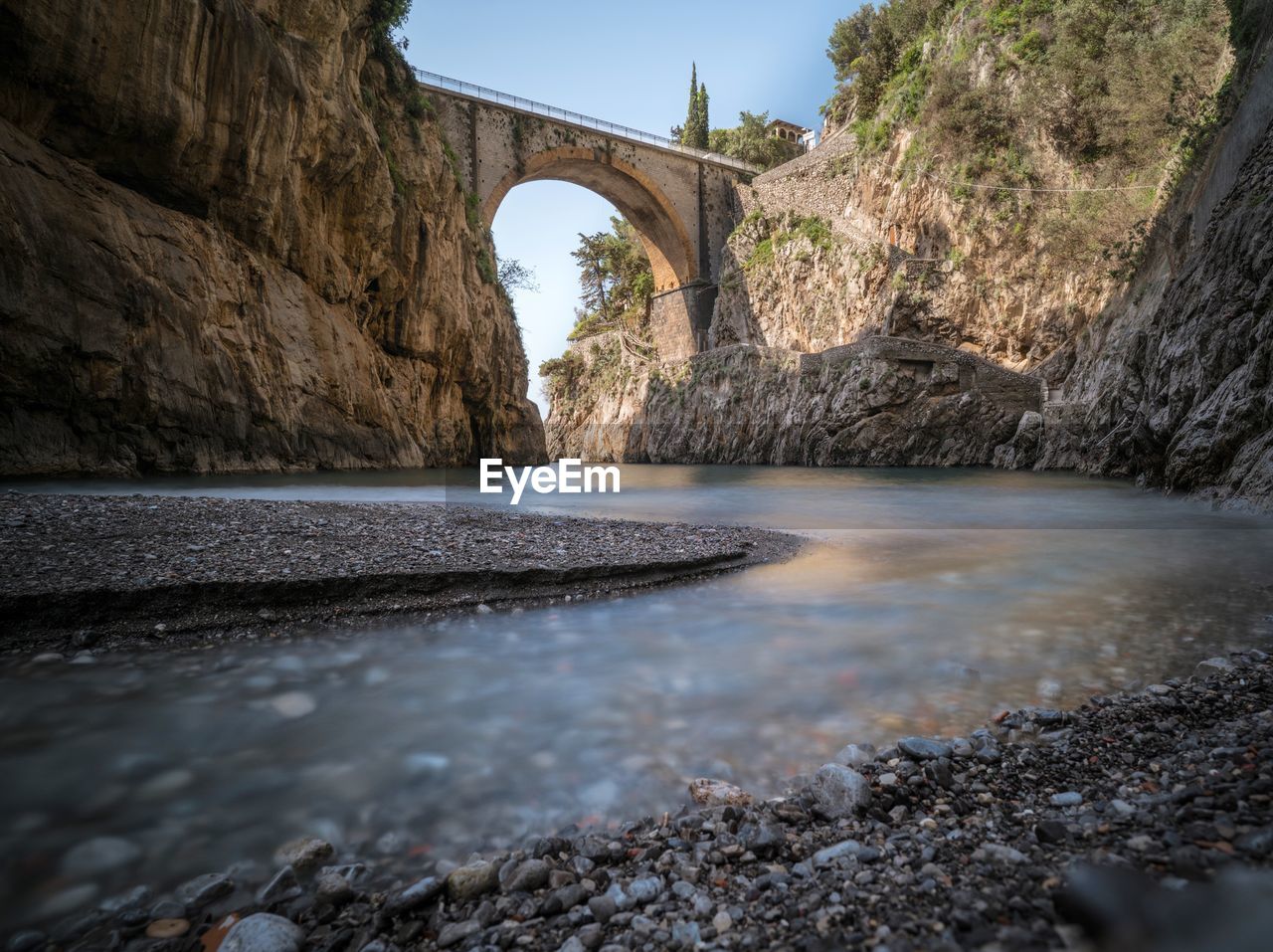 Arch bridge over river amidst rock formations